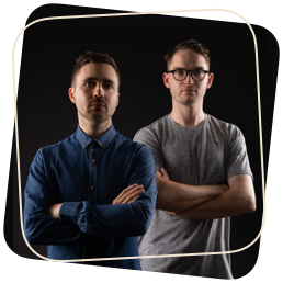 Two music producers posing in front of a black background in their boutique studio.